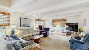 Ein geräumiges Wohnzimmer mit einer Couch, Sesseln, einem Couchtisch und einem Fernseher.