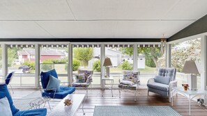 Ein überdachter Patio-Bereich mit Sitzgelegenheit, einem Tisch und Blick auf die Nachbarschaft.