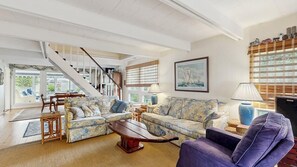 Ein Wohnzimmer mit Treppe, einer Sofagarnitur, einem Couchtisch und einer Lampe.