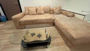 A beige sectional sofa with a glass coffee table in front.