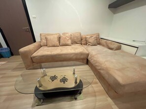 A beige sectional sofa with a glass coffee table in front.