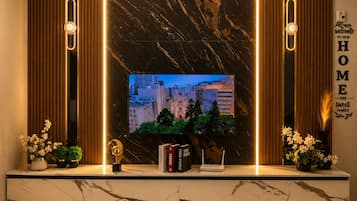 Un salon moderne avec un grand téléviseur, des étagères en marbre et une pancarte indiquant « Bienvenue chez nous ».
