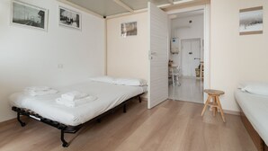 A room with a bed, a stool, and a door leading to a bathroom. - Comfortable 35m2 apartment, ideal for up to 5 people, located on the second floor of a building with lift.The accommodation is located in the Porta Romana district in a strategic position, a stone's throw from the Lodi Tibb M3 stop and the Porta Roman (Milan)