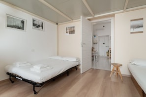 Una habitació amb un llit, un tamboret i una porta que dona a un bany.