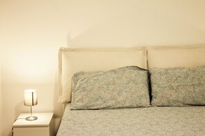 A bed with patterned bedding, a bedside lamp, and a white nightstand.