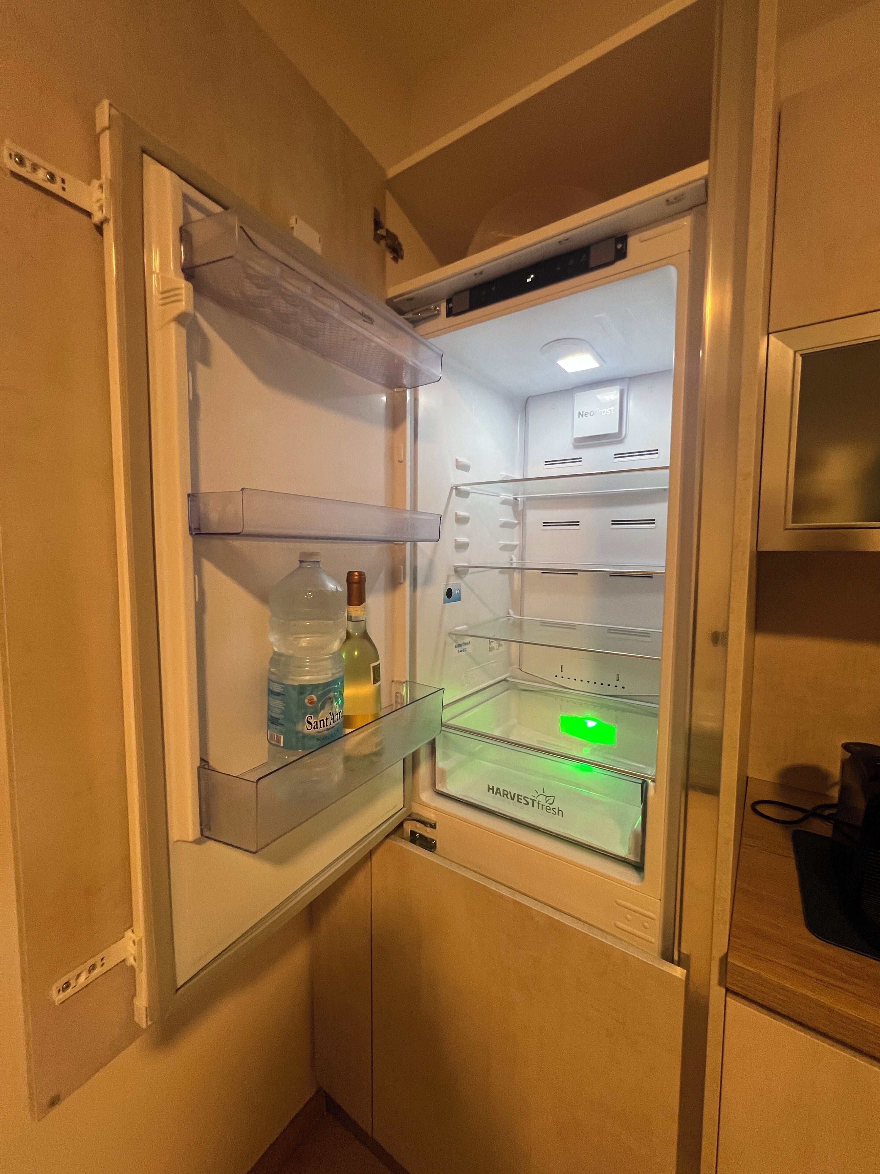 Un refrigerador con dispensador de agua, una botella de agua y un adhesivo verde en la puerta.