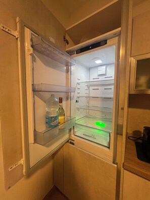 A refrigerator with a water dispenser, a bottle of water, and a green sticker on the door.