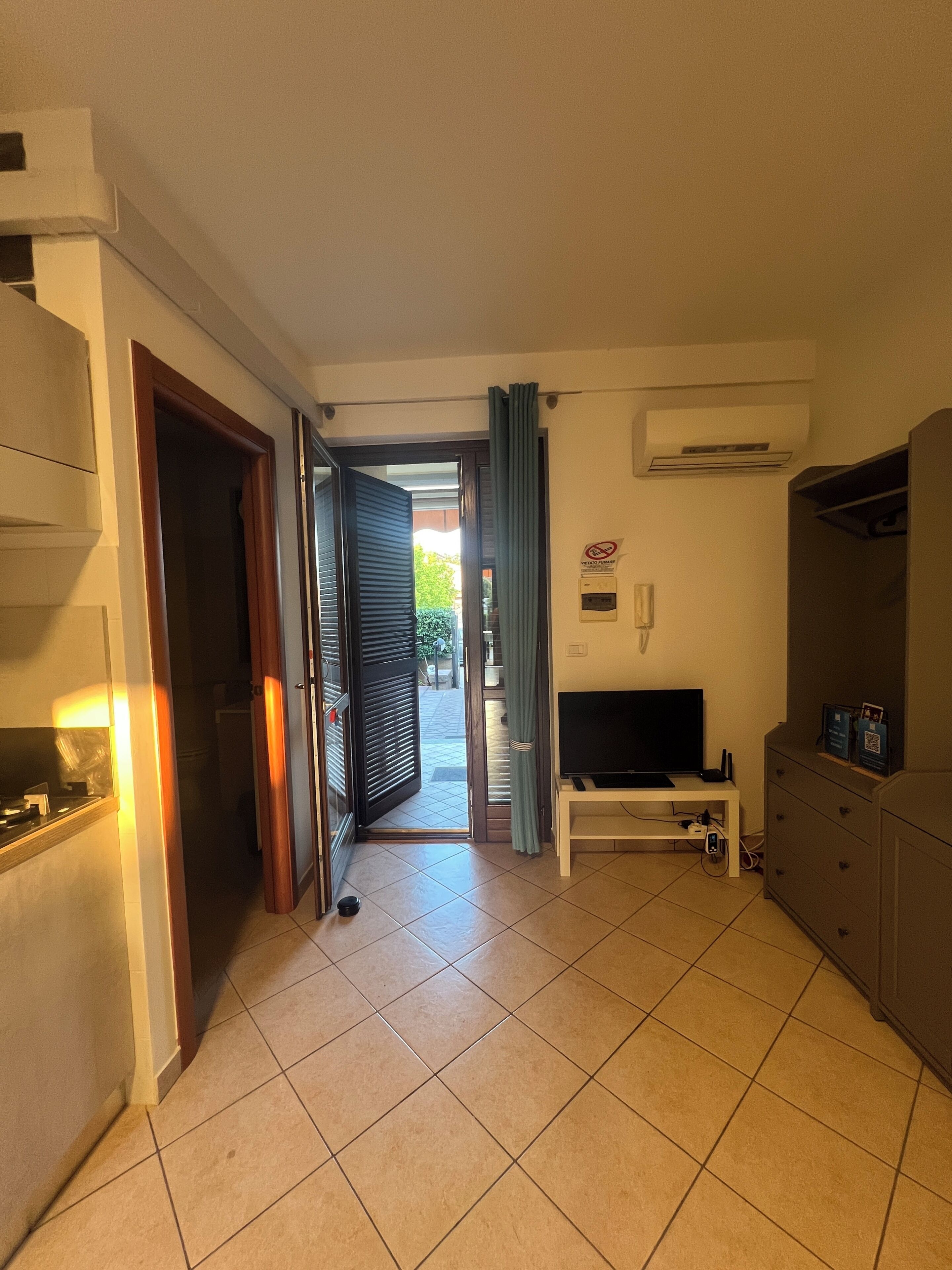 Een gang die uitkomt op een balkon met een televisie en een kast.