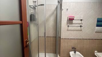 Ein Badezimmer mit einer Duschkabine, einem Bidet und einer Toilette.