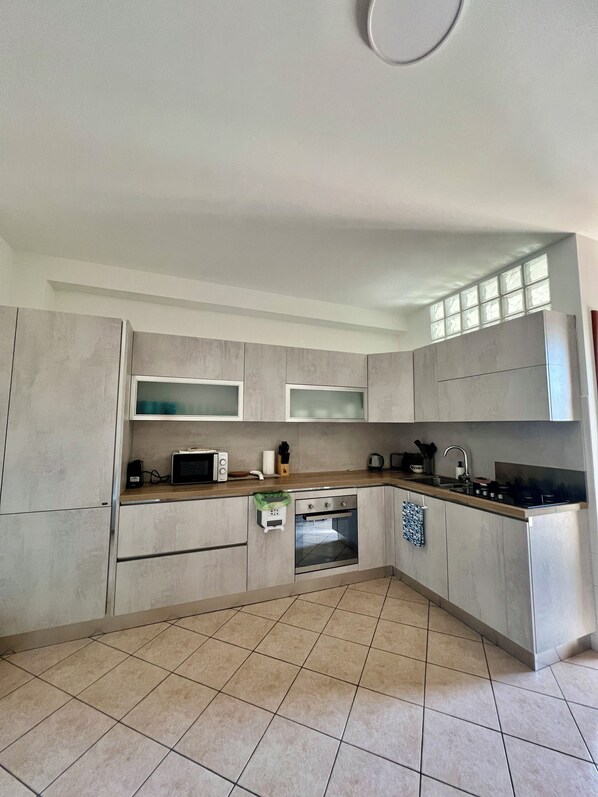A modern kitchen with a built-in oven, microwave, and a large window above the sink.