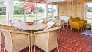 A room with a round table, wicker chairs, a yellow armchair, and a wooden wall. - 6 Person Holiday Home in Bindslev (Bindslev)