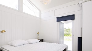 A bedroom with a bed, bedside table, lamp, and a window. - 6 Person Holiday Home in Bindslev (Bindslev)