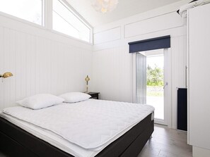 A bedroom with a bed, bedside table, lamp, and a window. - 6 Person Holiday Home in Bindslev (Bindslev)
