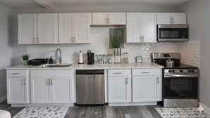 Una cocina moderna con armarios blancos, electrodomésticos de acero inoxidable y lavavajillas.