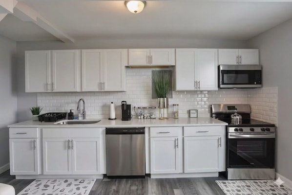 A modern kitchen with white cabinets, stainless steel appliances, and a dishwasher.