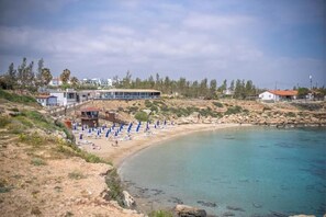 A coastal area with a beach, a building with a covered area, and a rocky shoreline. - Mambo Private Villa w/ Pool by the Beach (Paralimni)