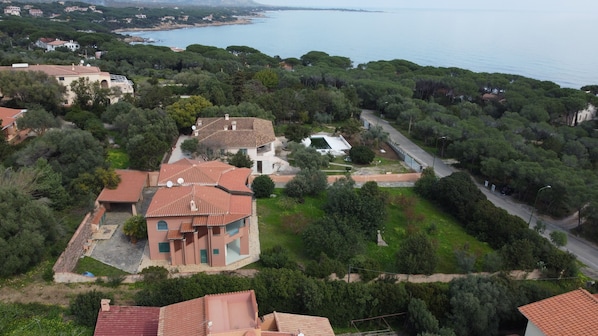 An aerial view of a residential area with houses, green spaces, and a coastline. - Hotiday Apartments Orosei (Orosei)