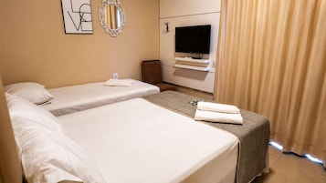 Quarto de hotel com duas camas, uma televisão, um espelho e uma cortina.