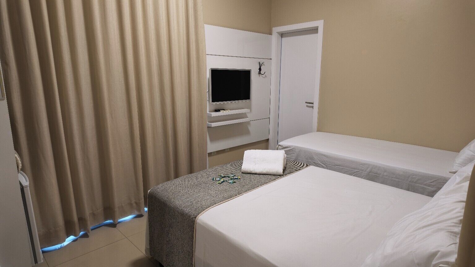 Ein Hotelzimmer mit Bett, Fernseher und Tür.