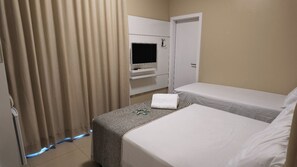 A hotel room with a bed, a TV, and a door.