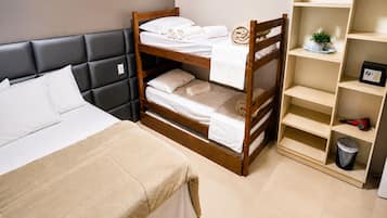 Una habitación de hotel con una cama individual, una litera y una estantería.