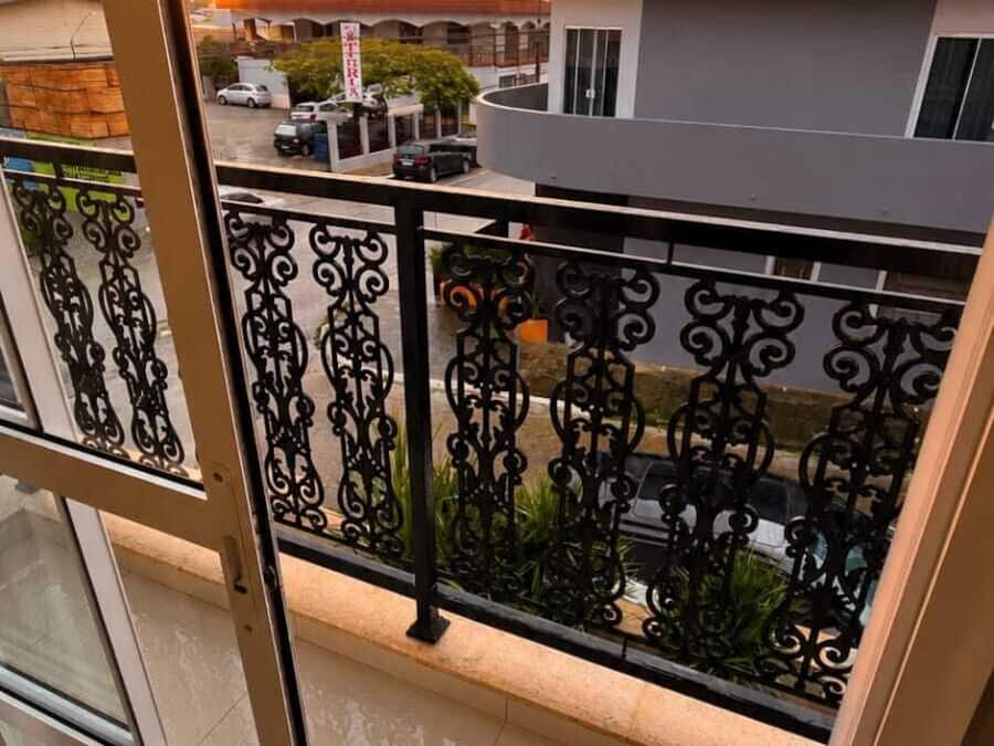 Un balcon avec une balustrade en métal, une vue sur le coucher de soleil et des bâtiments en arrière-plan.