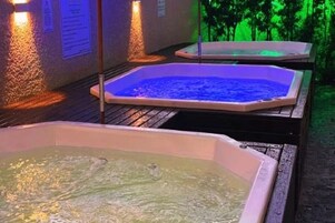 Dos jacuzzis con agua, rodeados de paredes con texto y una terraza de madera.