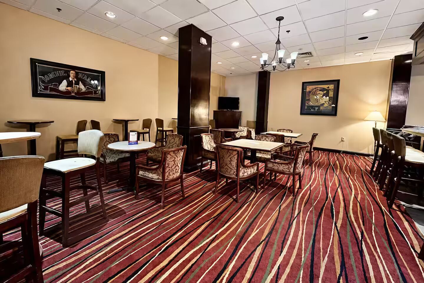 A hotel lobby with multiple seating areas, a television, and a patterned carpet.