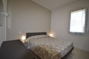 A bedroom with a bed, bedside tables, and a window with curtains.
