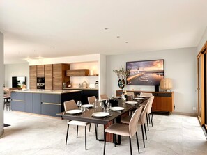 A modern kitchen with a central island, a dining area with a long table, and a large flat-screen TV mounted on the wall. - Family Home, a 10-minute walk from the beach - 4 suites with private bathrooms (Quiberon)