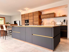 A modern kitchen with a central island, dark cabinetry, and a dining area with chairs. - Family Home, a 10-minute walk from the beach - 4 suites with private bathrooms (Quiberon)