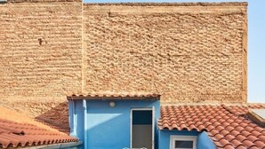 Un pati amb taula i cadires, una finestra petita i vista a una paret de maó.