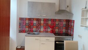Una cocina compacta con armarios blancos, un salpicadero colorido, una estufa y un comedor.