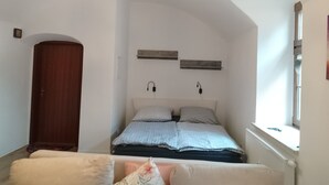 Un dormitorio con cama, armario, ventana y un diseño de techo único.