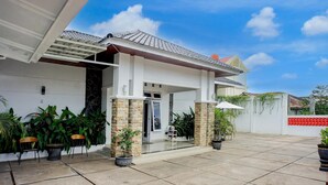 Une maison moderne avec un patio carrelé, des plantes en pot et un ciel dégagé.