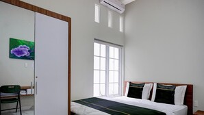 Une chambre d’hôtel avec un lit, une chaise, une fenêtre et un tableau au mur.