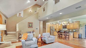A spacious living area with a staircase, a kitchen with bar stools, and a dining area. - Last Chance Ranch - Hallsville TX (Hallsville)