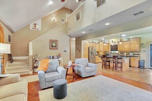 A spacious living area with a staircase, a kitchen with bar stools, and a dining area.