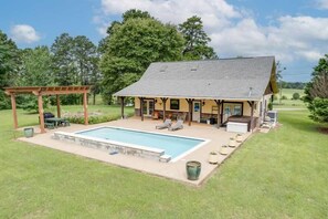 A house with a swimming pool, outdoor seating, and a covered patio.