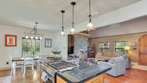A spacious kitchen with a large island, a dining area with white chairs, and a cozy living room with a fireplace. - Last Chance Ranch - Hallsville TX (Hallsville)