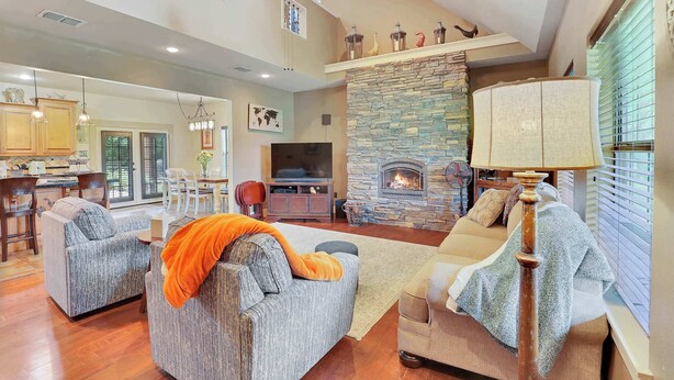 A spacious living area with a stone fireplace, two sofas, a dining area, and a kitchen. - Last Chance Ranch - Hallsville TX (Hallsville)