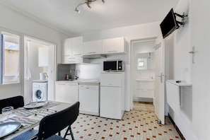 A compact kitchen with white cabinetry, a microwave, a dishwasher, and a washing machine. - Apartment 'Les Landes' with Shared Terrace, Garden, and Wi-Fi (Saint-Quay-Portrieux)