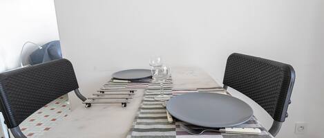 A dining table with chairs, a glass, and cutlery.