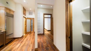 Ein Flur mit Holzboden, einem Kühlschrank und einem weißen Kleiderschrank mit Regalen.