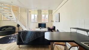 Ein zeitgemäßer Wohnbereich mit Sofa, Esstisch, Fernseher und einer Treppe.