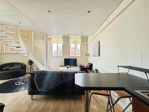 Ein zeitgemäßer Wohnbereich mit Sofa, Esstisch, Fernseher und einer Treppe.