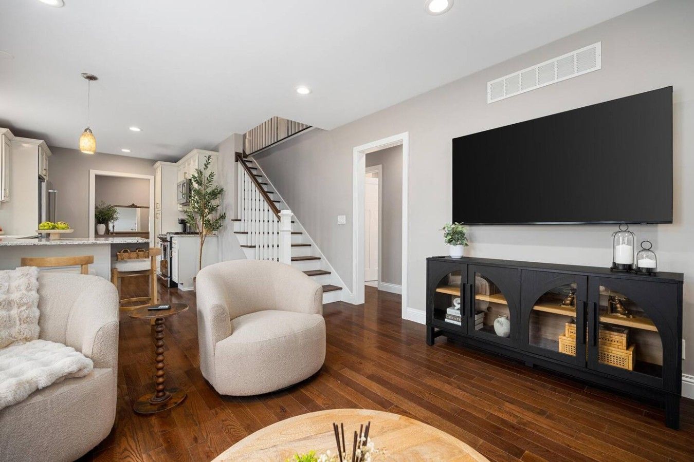 A modern living room with a sofa, armchair, and a console table with decorative items.