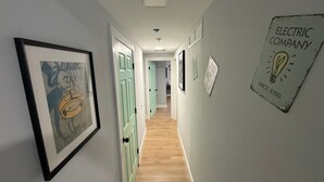 En hall med inramade konstverk, en ljusströmbrytare och en skylt som är monterad på väggen.