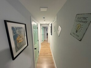 Ein Korridor mit gerahmten Bildern, einem Lichtschalter und einem an der Wand befestigten Schild.