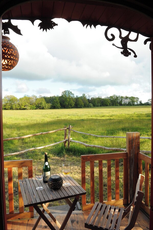 A wooden deck with a table, chairs, and a bottle of champagne.